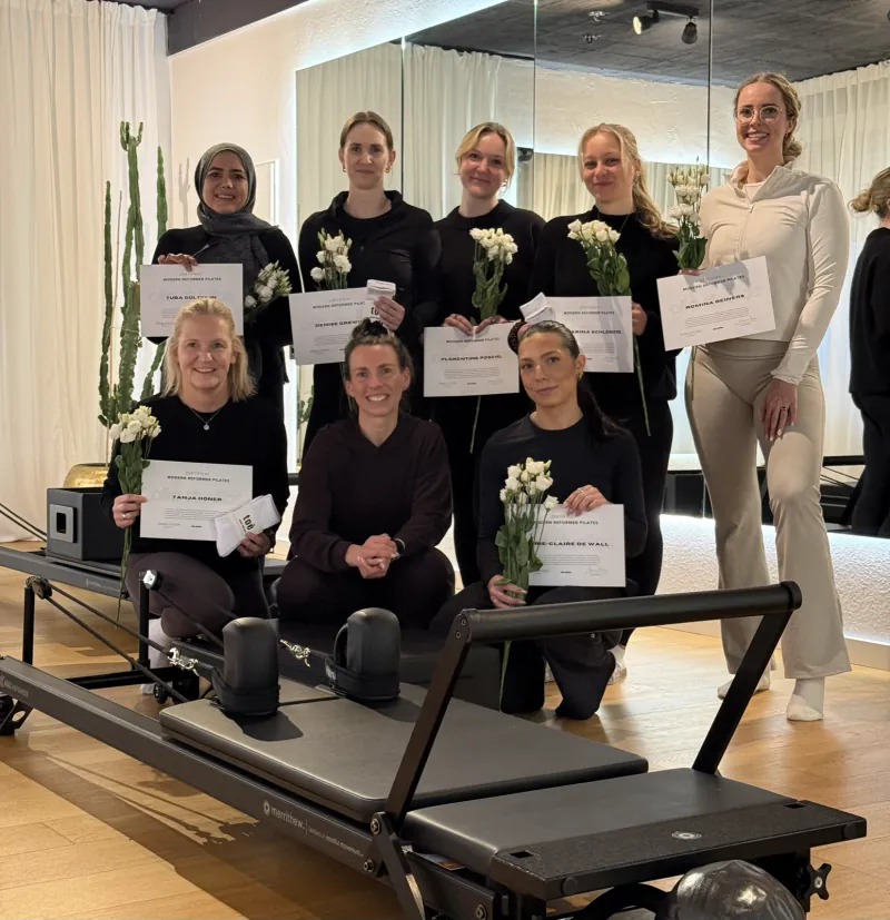 Gruppenfoto: Absolventinnen der Reformer Pilates Ausbildung mit ihren Zertifikaten am Reformer im olia Studio in Rietberg